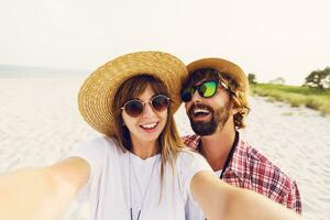 Couple or best friends man and woman having fun on summer sunny beach . Wearing straw hat, sunglasses, stylish  shirts . photo