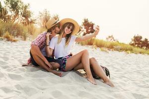 Couple or best friends man and woman having fun on summer sunny beach . Wearing straw hat, sunglasses, stylish  shirts . photo