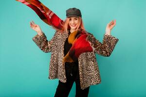 Close up indoor studio fashion portrait of gorgeous woman in stylish winter fluffy  coat with leopard print  playing with scarf and  posing on bright  turquoise  background. photo