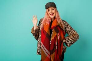 studio fashion portrait of gorgeous woman in stylish winter fluffy  coat with leopard print  playing with scarf and  posing on vivid turquoise  background. photo