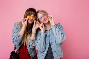 dos hermanas teniendo divertido y haciendo mueca terminado rosado antecedentes. foto