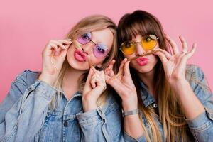 Two sisters having fun  and making grimace over pink background. photo