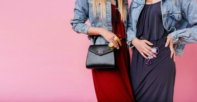 Fashion details of two pretty women posing together over pink isolate background.  Autumn trendy outfit.Similar  jeans jacket. Stylish sunglasses. Leather bag. photo