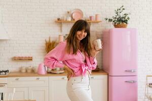 Stylish brunette woman enjoing cozy morning with cup of tea in light modern kitchen. photo