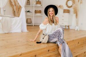 Cozy home atmosphere. Stylish blond  woman in  linen wear  posing in light modern interior studio. photo