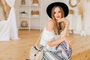 Cozy home atmosphere. Stylish blond  woman in  linen wear  posing in light modern interior studio. photo