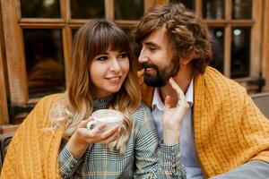 Close up cozy warm portrait of happy hugging couple in love.  Handsome man and pretty woman having breakfast and drinking coffee on terrace. photo