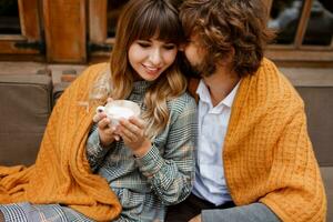 Close up cozy warm portrait of happy hugging couple in love.  Handsome man and pretty woman having breakfast and drinking coffee on terrace. photo