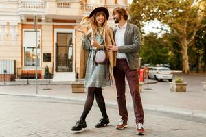 lleno longitud imagen de hermosa de moda Pareja en amor caminando en soleado primavera ciudad mientras tener una cita. disfrutando Luna de miel en europeo ciudad. foto