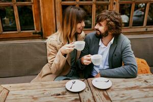 romántico momentos de elegante Pareja en amor sentado en un cafetería, Bebiendo café, teniendo un conversacion y disfrutando el hora gastar con cada otro. foto