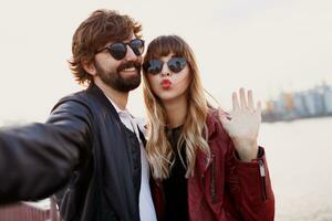 cerca arriba yo retrato de linda juguetón Pareja teniendo divertido y gasto romántico momentos juntos . vistiendo elegante cuero chaqueta y Gafas de sol. foto