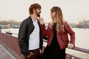 Romantic moments of stylish couple in love having a conversation and enjoying the time spend with each other . Handsome man with his wife walking on the bridge. photo