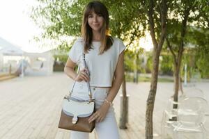 al aire libre verano retrato de alegre mujer en blanco camiseta y pantalones caminando en el parque. foto