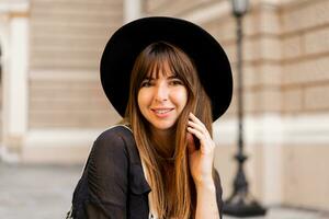 Close up  portrait  of stylish brunette woman in casual outfit  and black hat. Enjoing vacation in european city. photo