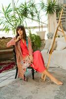 Portrait of beautiful artist woman in bohemian outfit posing with brush and palette in her art studio. photo