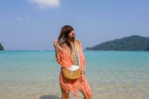 Outdoor summer portrait of stylish tan  pensive woman  in trendy boho beach dress with embroidery and tassel. Straw  bag. photo