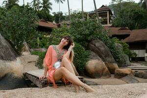 Beautiful woman in boho dress  posing near luxury resort.  Enjoing vacation on tropical island. photo