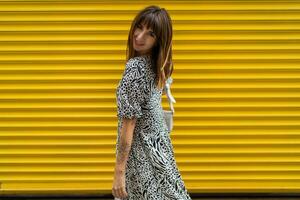 Graceful woman with tatoo on hand posing over yellow  urban wall. photo