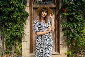 Outdoor summer portrait of beautiful woman wolking in old european city. Wearing straw hat. photo