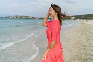 Summer image of happy sexy woman in gorgeous pink dress posing on the beach. photo