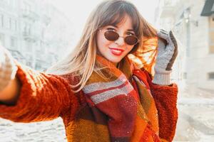 Pretty  long haired woman making self portrait in sunny winter day. Old city background. photo