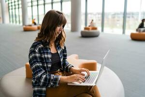 Happy woman  using lap top while sitting at airport lounge. photo