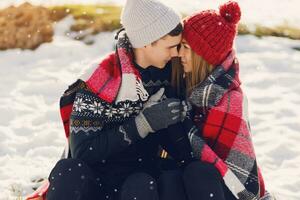 Close up winter portrait of young couple in love hugging  under the blanket, wearing  knitted hat and gloves . Soft toned photo. Romantic mood. Holidays concept. Snowfall. photo