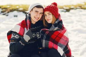 Close up winter portrait of young couple in love hugging  under the blanket, wearing  knitted hat and gloves . Soft toned photo. Romantic mood. Holidays concept. Snowfall. photo