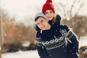 Romantic winter scene, happy young couple  in love having fun  in  sunny  forest. Wearing hats and warm cozy sweater. photo