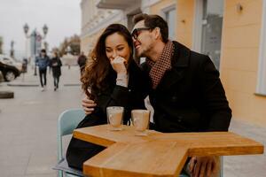 Fashionable couple in love sitting in street cafe  and drinking hot coffee while traveling in Europe. photo