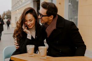 Fashionable couple in love sitting in street cafe  and drinking hot coffee while traveling in Europe. photo