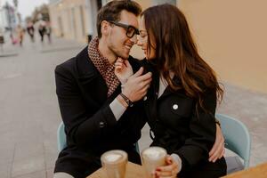 hermoso hombre y su elegante Novia abrazando y disfrutando caliente bebida en café . foto