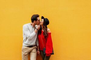 Playful couple in love posing over yellow wall. Traveling people. photo