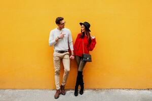 Full height image of  playful couple in love posing over yellow wall. photo