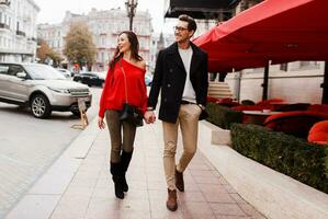 Outdoor fashion image of elegant couple walking in city. Happy romantic moments. photo