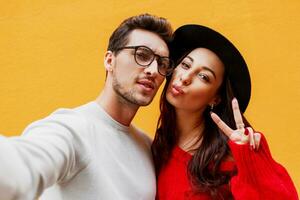 Close up  lifestyle portrait of Happy girl with her boyfriend making self portrait over yellow wall. photo