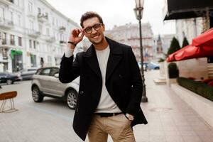 joven hombre vistiendo otoño ropa caminando en el calle. elegante chico con moderno peinado en urbano antecedentes. foto