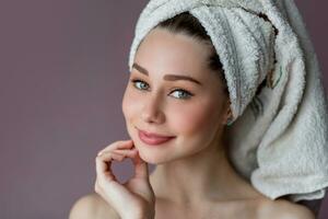 Arttractive smiling young woman wearing bathrobe and towel over her head standing  over pink background purple background. photo