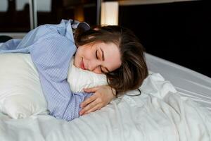 Cute woman lying  on her   stomach   on the bed and sleep . Wearing stylish black lingerie and striped  boyfriend shirt. photo