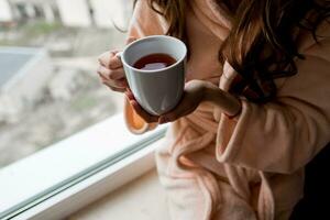 Woman in bathrobe  holding cup of hot tea. Autumn mood. photo