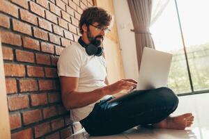 Handsome hipster man with beard using lap top at home photo