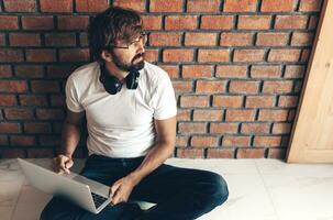 Handsome hipster man with beard using lap top at home photo