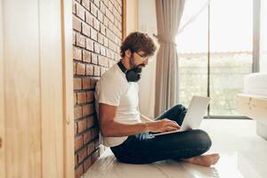 Handsome hipster man with beard using lap top at home photo