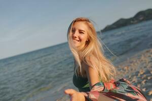 Outdoor summer image of sexy sportive blond woman posing on the beach. Wearing jeans shorts and green top. Fashion details. photo