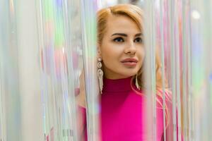 Studio photo of shiny blond woman in sexy pink dress. Perfect wavy hairs. New year  party.