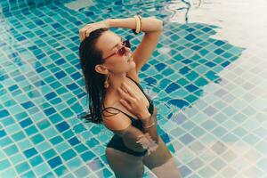 Gorgeous slim woman with perfect figure posing in swimming pool photo