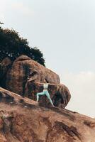 agraciado mujer práctica yoga en rocas foto