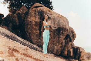 Graceful woman practice yoga  on rocks. photo