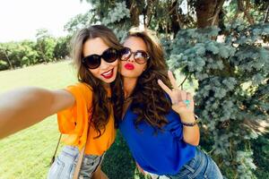 Close up lifestyle  image  of two best friends having fun and making self  portrait  together.    Bright colors.Wearing casual outfit. photo