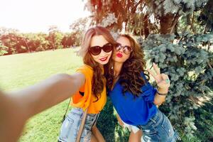 Close up lifestyle  image  of two best friends having fun and making self  portrait  together.    Bright colors.Wearing casual outfit. photo